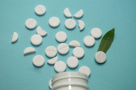 White pills with green leaf on blue background. Focus on foreground.の写真素材