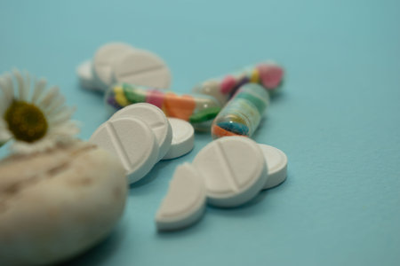 Assorted pharmaceutical medicine pills, tablets and capsules on blue background.