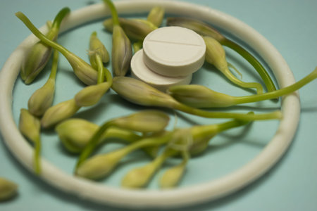 Close-up of white pills and green flowers on blue background.の写真素材