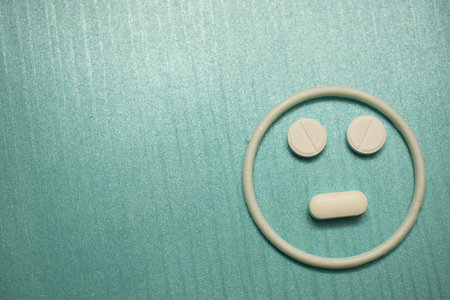 Medical concept with pills forming sad and neutral face on blue background