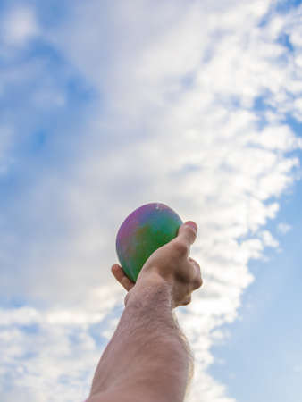 Colorful mango in a male hand with a blue sky backgroundの写真素材