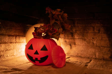 Creepy and terrifying halloween scene. Orange pumpkin, dry grass and a red moon or circular light behind in a stone backgroundの写真素材