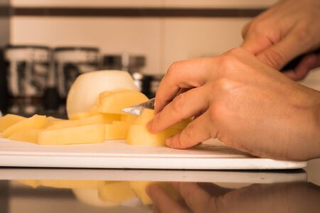 Woman hands cutting potatoes and onions in the kitchenの写真素材