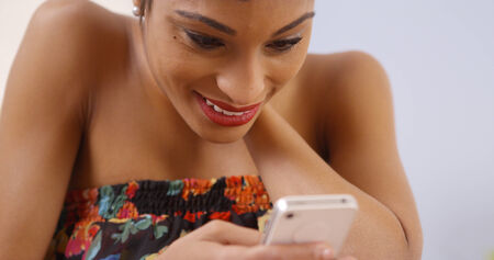 Black woman happily using smartphoneの写真素材