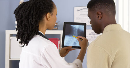 African American patient talking with female physician about x rays on tabletの写真素材