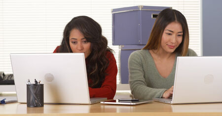 Happy multi-ethnic colleagues working on laptops