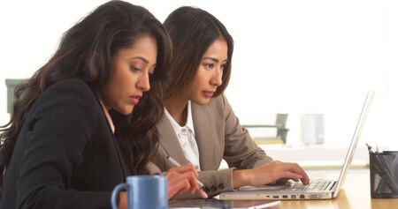 Multi-ethnic businesswomen doing research at deskの写真素材