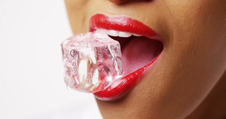 Close up of woman holding ice in mouth on white backgroundの写真素材