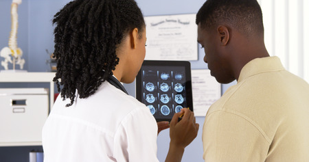 African American doctor talking to patient about brain scans on tabletの写真素材