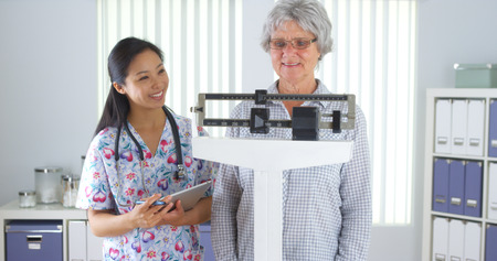 Chinese nurse weighing elderly patientの写真素材