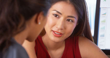 Asian businesswoman having a discussion with Mexican colleagueの写真素材