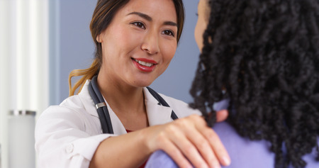 Close up of Japanese physician with hand on shoulder of patientの写真素材