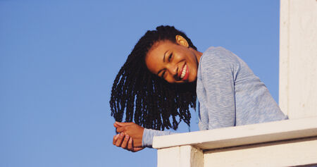 Happy black woman leaning on rail smilingの写真素材