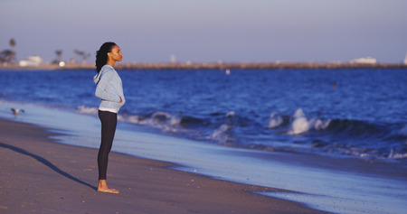 Black woman enjoying the ocean view until waves comeの写真素材