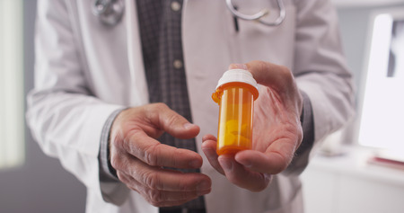 Senior doctor holding prescription bottle.の写真素材