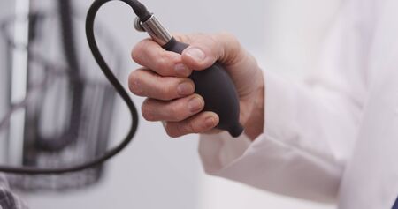 A doctor's hand pumping monitor to check blood pressure.の写真素材