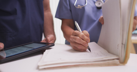 Close-up of mature female nurse writing in a patient's folder.の写真素材