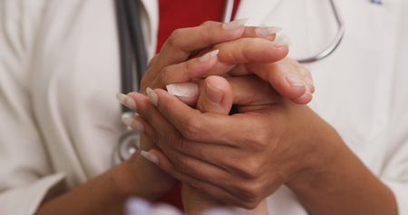 Close up of doctor's hands holding patient's handの写真素材