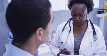 Tight shot of African female doctor explaining to young patient health conditionの写真素材
