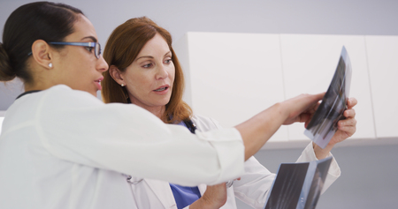 Two medical colleagues looking at xrays of patients wrist and hand inside office