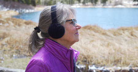 Close view of joyful senior lady observing nature with wind blowing her hairの写真素材