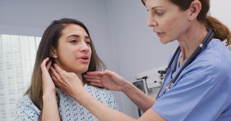 Senior nurse examines womans lymph nodes on neck to determine if swollenの写真素材