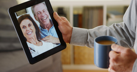 Closeup of middle-aged man talking a friends on tablet