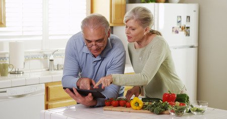 Senior couple using tablet and cookingの写真素材