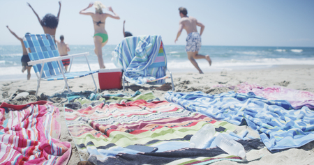 Group of young multi ethnic friends running to beach shoreの写真素材