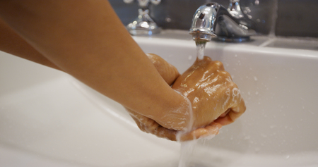 Young pretty black woman washing her handsの写真素材