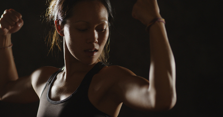 Fit young Asian woman flexing her armsの写真素材