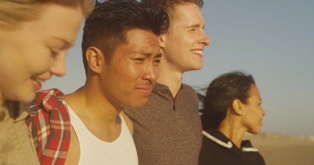 Friends smiling and looking towards the oceanの写真素材