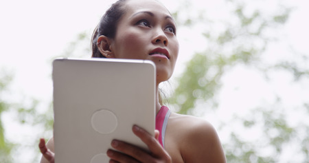Young active woman looking at tablet at the park wanderingの写真素材