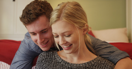 Cute Couple smiling using tablet in their bedroom