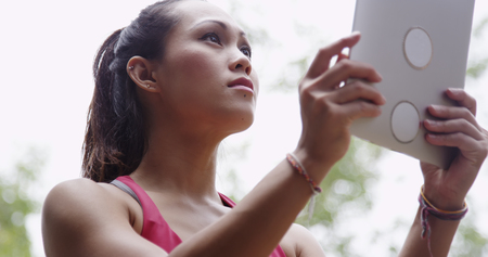 Active young woman reading tablet after workout in the parkの写真素材