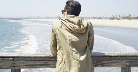 Young Hispanic man staring into horizon from a pier