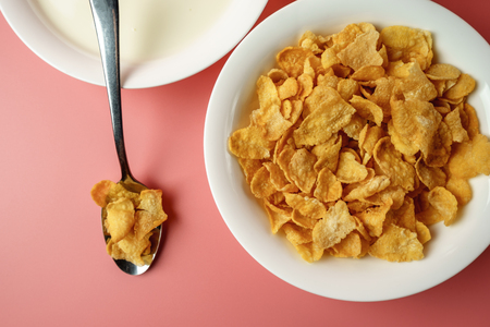 Corn flakes and yogurt in white bowl  place on pink background