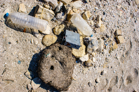 Plastic bottles and a broken car radio litter the beach.の写真素材