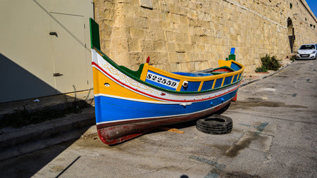 A traditional wooden Maltese fishing boat (Luzzu) on land outside the ancient city walls of Valletta on the Mediterranean Island of Maltaのeditorial素材