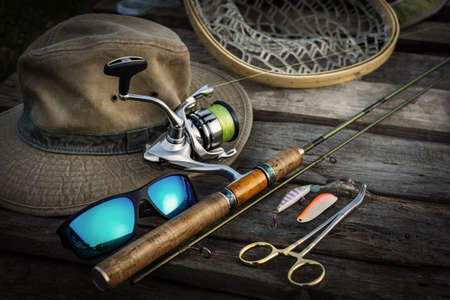 Fishing tackle on a wooden background. Fishing rod, reel, fishing rod, glasses, fishing rod and hat.の写真素材