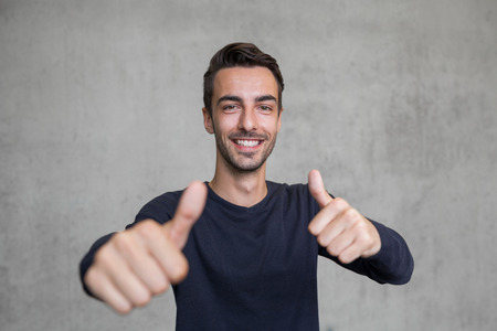 thumps up portrait of a young man smilingの写真素材