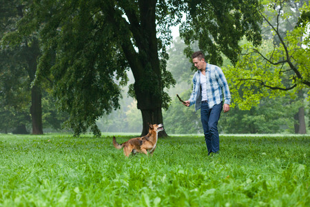 young man playing with his dog and stickの写真素材