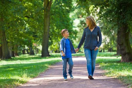 young woman with son walking through avenueの写真素材