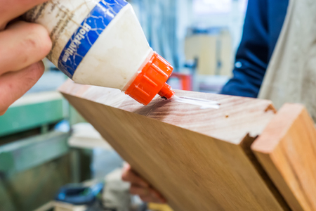 using wood glue to glue boards for furniture construction at carpentryの写真素材