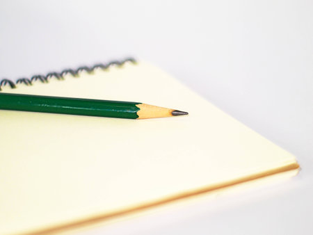 green pencil on a plain ring binder notebook, side viewの写真素材