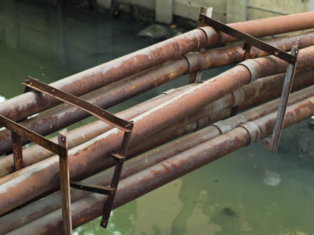 rusty water pipes above a dirty canalの写真素材