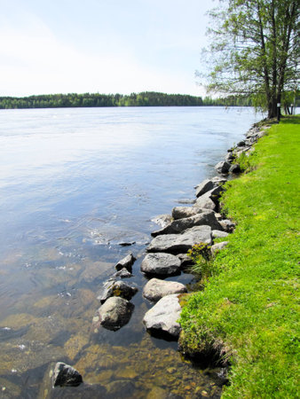 Bank of the river with stones on blue sky backgroundの写真素材