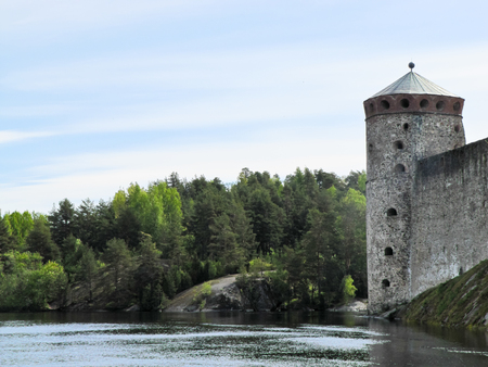 old castle by the river on a background of forest and blue skyのeditorial素材