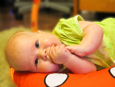 a small child in a green suit lying on its side on the pillowの写真素材