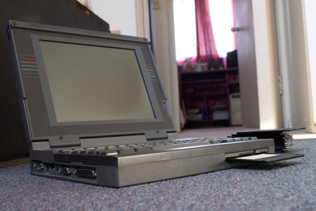 hands of a person using a floppy disk in an antique laptop